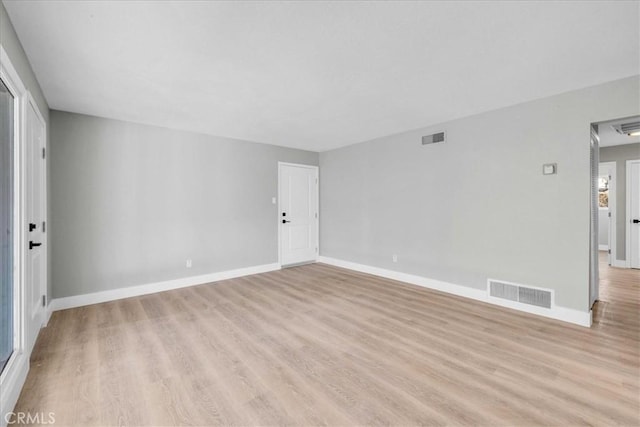 spare room with light wood-style flooring, visible vents, and baseboards