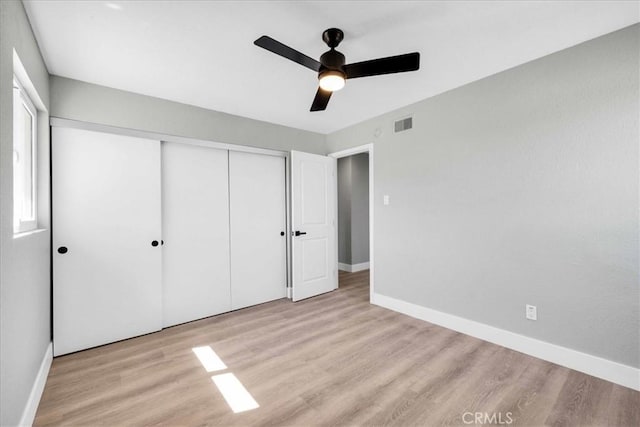 unfurnished bedroom featuring a ceiling fan, a closet, baseboards, and wood finished floors