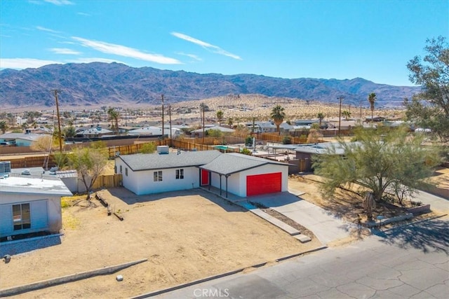 view of front facade with driveway, a garage, fence, and a mountain view