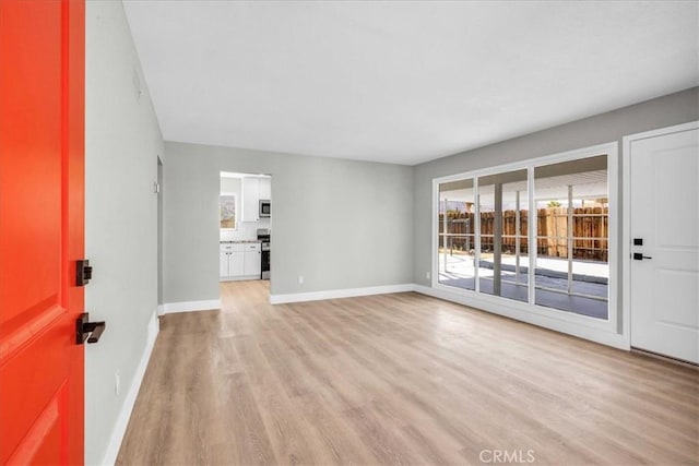 unfurnished living room with light wood-style flooring and baseboards