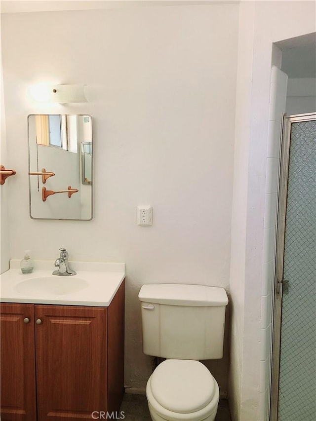 bathroom with toilet, a stall shower, and vanity