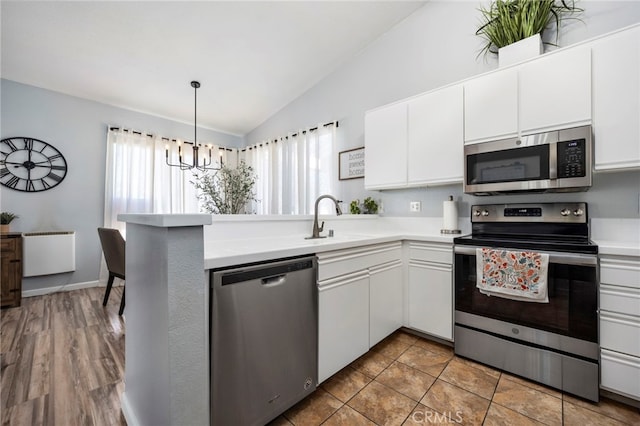 kitchen with a healthy amount of sunlight, radiator heating unit, appliances with stainless steel finishes, and lofted ceiling