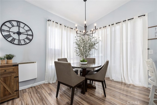 dining space featuring light wood-type flooring, baseboards, and an inviting chandelier