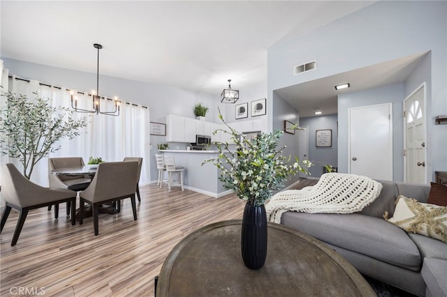 living area with a chandelier, visible vents, light wood-style flooring, and baseboards