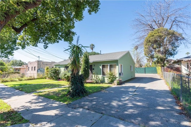 view of front of property with aphalt driveway, a front lawn, fence, and stucco siding