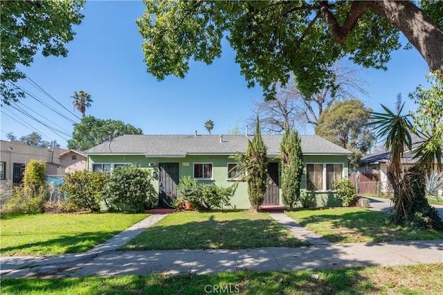 view of front of house featuring fence, a front lawn, and stucco siding