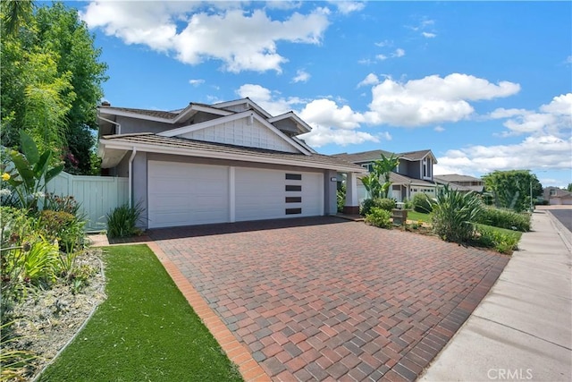 view of front facade featuring decorative driveway, fence, and an attached garage