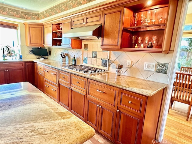 kitchen with stainless steel gas cooktop, under cabinet range hood, decorative backsplash, and open shelves