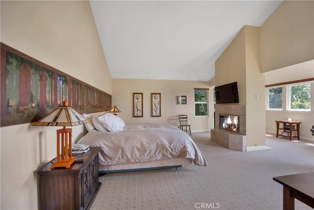 carpeted bedroom with high vaulted ceiling, a tile fireplace, and baseboards