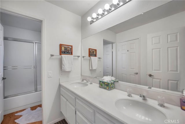 full bathroom featuring double vanity, shower / bath combination with glass door, and a sink