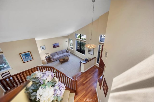 living area with high vaulted ceiling, a chandelier, and wood finished floors