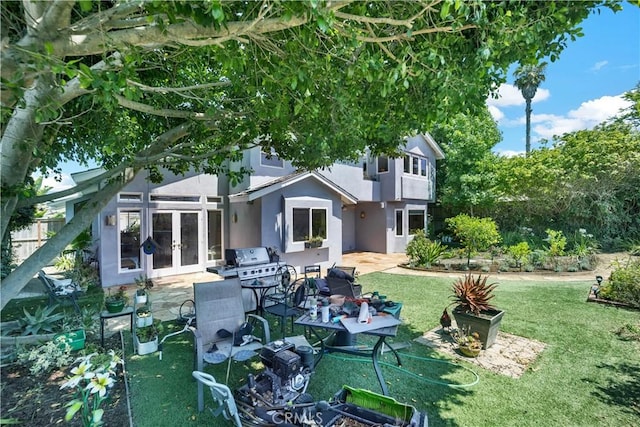 rear view of property featuring french doors, a patio area, a yard, and stucco siding