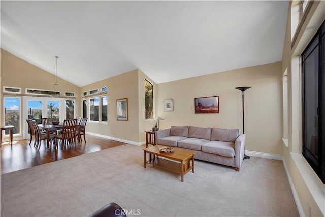 living area with carpet floors, baseboards, and high vaulted ceiling