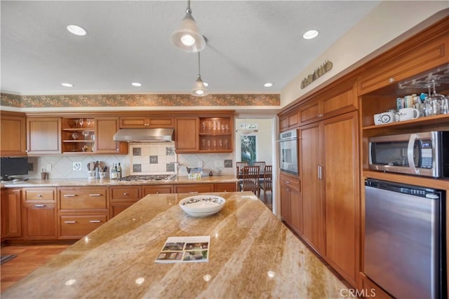 kitchen with open shelves, brown cabinets, under cabinet range hood, and stainless steel appliances