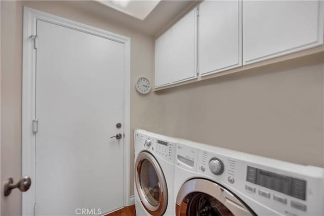 clothes washing area featuring cabinet space and washer and clothes dryer