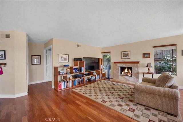 living room with wood finished floors, visible vents, baseboards, and a premium fireplace