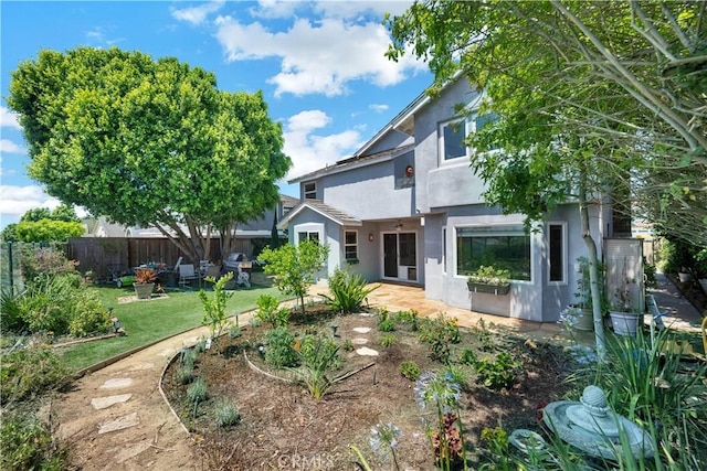 view of front of house with a patio, a front lawn, fence, and stucco siding