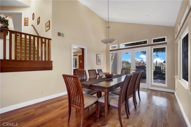 dining area featuring high vaulted ceiling, wood finished floors, visible vents, baseboards, and french doors