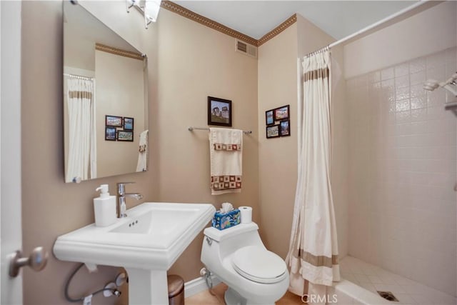 full bathroom featuring tiled shower, a sink, visible vents, and toilet