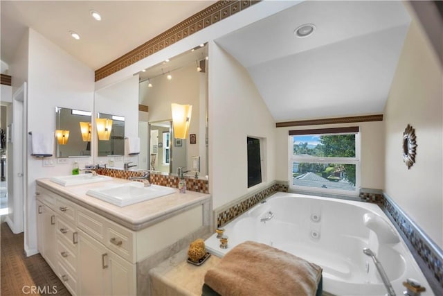 bathroom with lofted ceiling, double vanity, a sink, and a whirlpool tub