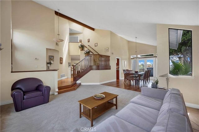 carpeted living room with high vaulted ceiling, stairway, visible vents, and baseboards