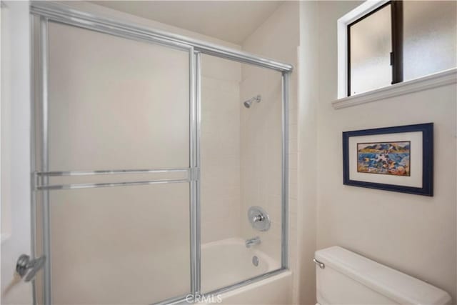 full bathroom with toilet and shower / bath combination with glass door