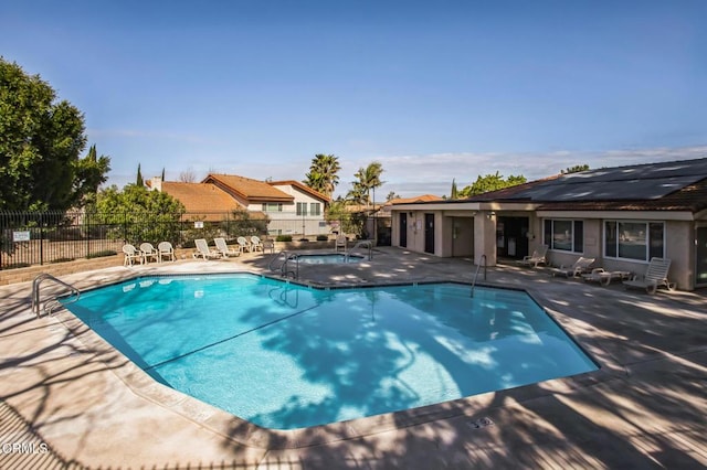 community pool featuring a community hot tub, a patio area, and fence