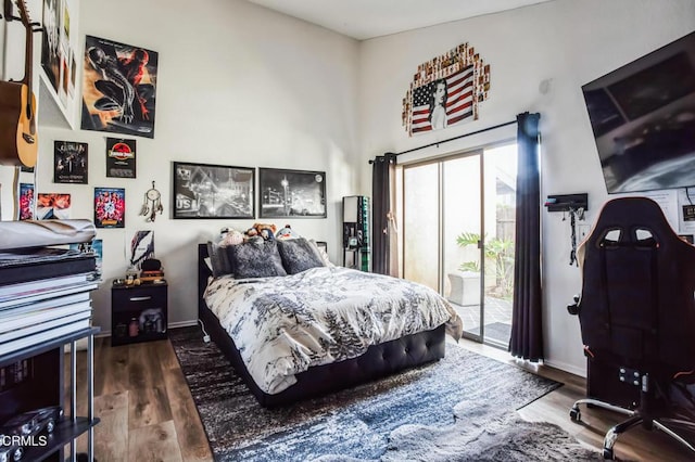 bedroom featuring access to outside, wood finished floors, and baseboards