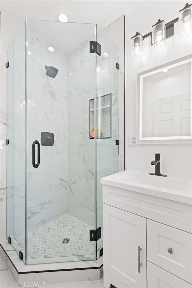 bathroom with a marble finish shower, vanity, and recessed lighting