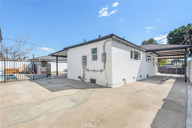 view of home's exterior featuring an attached carport, crawl space, fence, and stucco siding