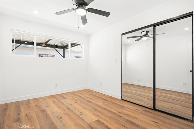 unfurnished bedroom featuring ceiling fan, recessed lighting, wood finished floors, baseboards, and a closet