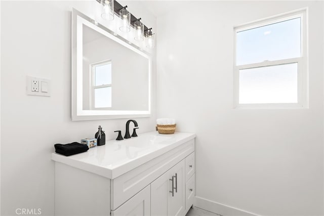 bathroom featuring plenty of natural light, vanity, and baseboards