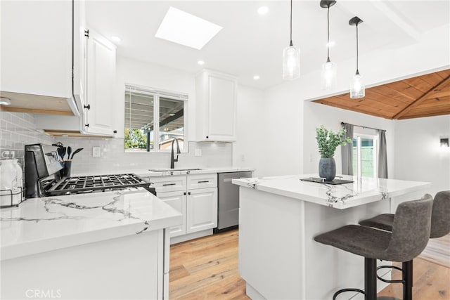 kitchen featuring decorative backsplash, a kitchen island, stainless steel appliances, a healthy amount of sunlight, and a sink