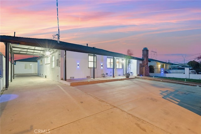 back of house at dusk featuring fence and stucco siding