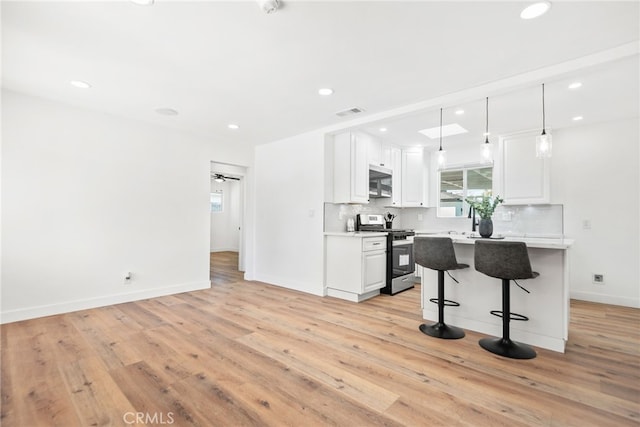 kitchen featuring a breakfast bar, white cabinetry, light countertops, appliances with stainless steel finishes, and tasteful backsplash