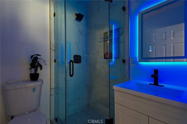 bathroom featuring toilet, a marble finish shower, and vanity