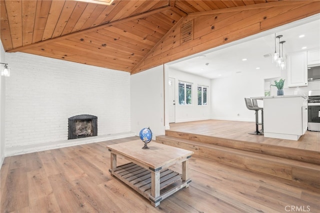 living area featuring visible vents, wooden ceiling, vaulted ceiling, light wood-type flooring, and a brick fireplace