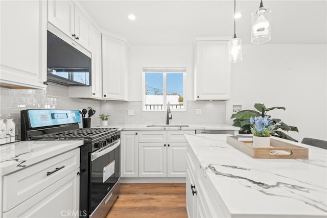 kitchen with stainless steel appliances, a sink, white cabinetry, light wood-type flooring, and decorative backsplash