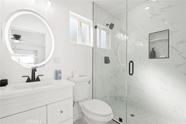 bathroom with toilet, vanity, a marble finish shower, and ceiling fan