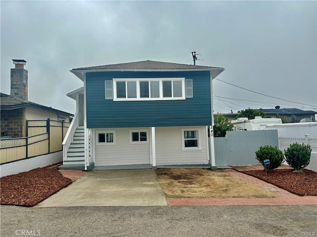 rear view of property featuring fence and stairway