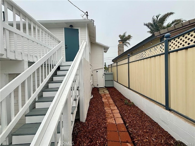 view of property exterior featuring fence and stairs