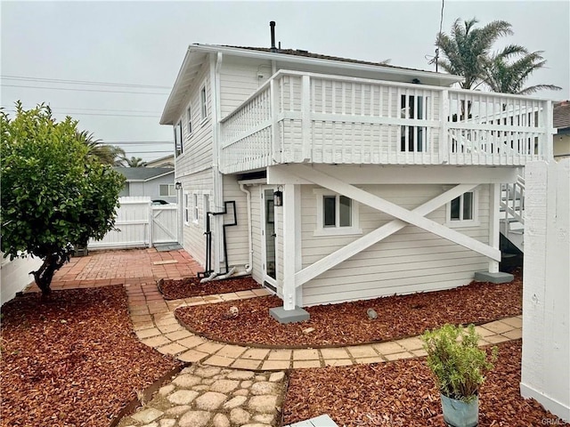 view of side of property with a gate, fence, and stairs