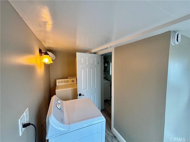 laundry area featuring laundry area, baseboards, wood finished floors, and washing machine and clothes dryer