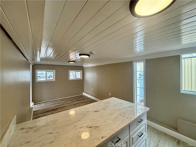 kitchen featuring light stone countertops, wood ceiling, baseboards, and white cabinets