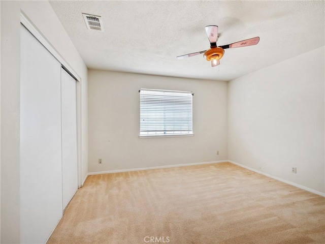 unfurnished bedroom featuring baseboards, visible vents, a textured ceiling, carpet flooring, and a closet