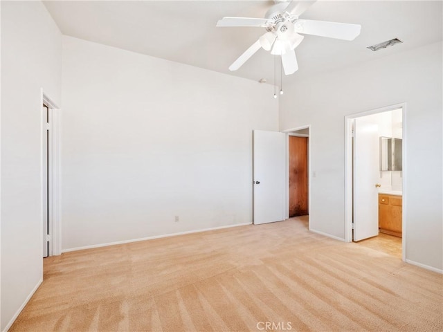 unfurnished bedroom with visible vents, baseboards, connected bathroom, light colored carpet, and a towering ceiling