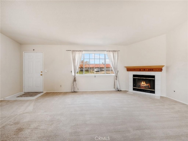 unfurnished living room with carpet, baseboards, and a tiled fireplace