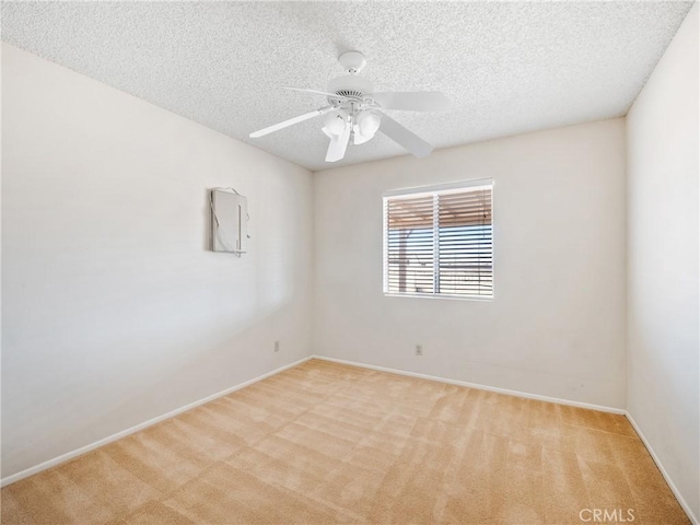 empty room featuring light carpet, baseboards, a ceiling fan, and a textured ceiling