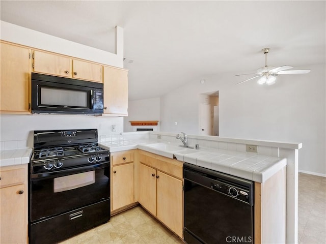 kitchen with a sink, a peninsula, black appliances, and light brown cabinetry