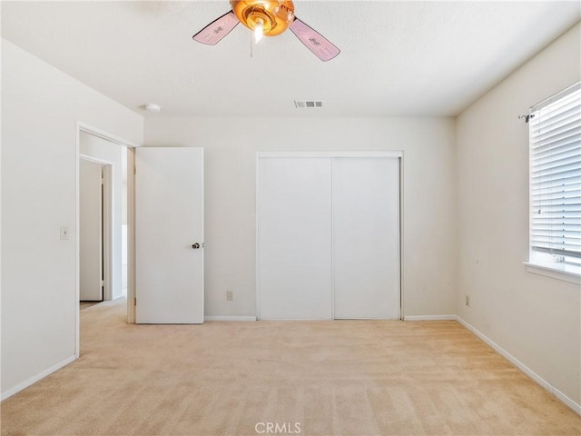 unfurnished bedroom featuring ceiling fan, visible vents, baseboards, a closet, and carpet